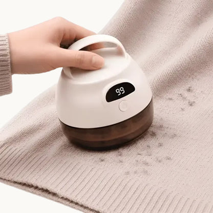 Mano utilizando el removedor de pelusas sobre un tejido claro con bolitas.